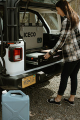Woman pulls out Nomad Kitchen from rv rental, with ICECO fridge inside. Ready for camping in Alaska.