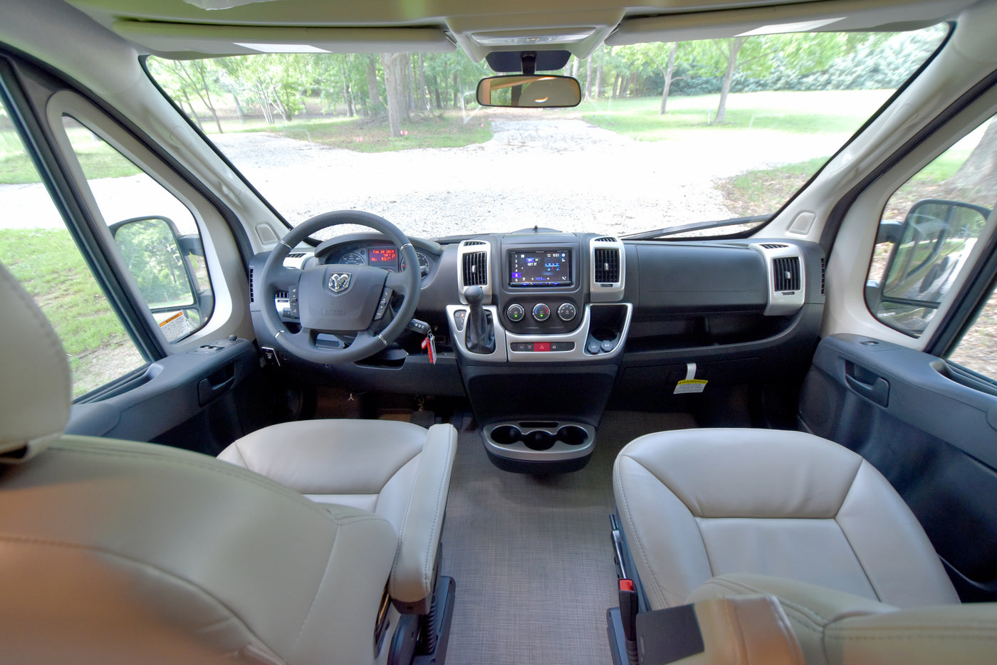 Spacious RV rental cockpit: light-colored seats, a detailed dashboard, and a clear view of the road ahead. — photo 5