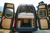 Explore this RV rental: a custom camper van conversion with a comfortable bed, smart storage, and control panels visible.