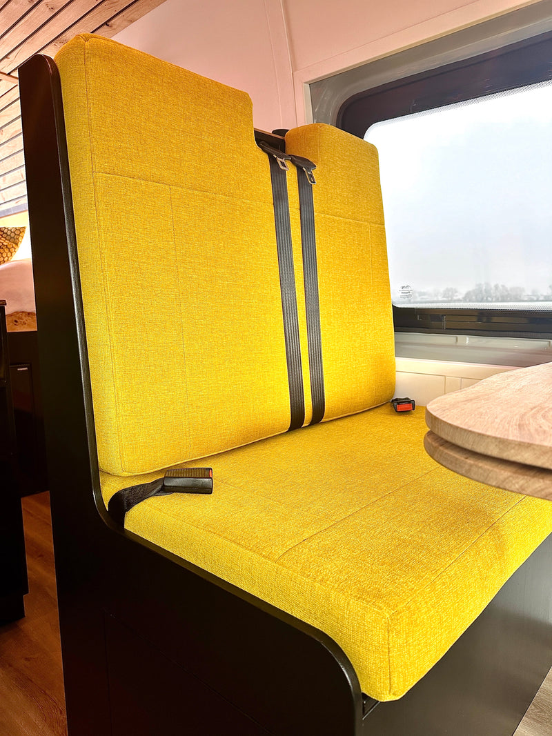RV rental interior: Bright yellow bench seating with seat belts and a window view, offering comfort for your journey. — photo 18