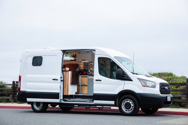 A bright white Ford Transit camper van, equipped for RV rental, showcases its cozy, custom interior through an open side door. — photo 19