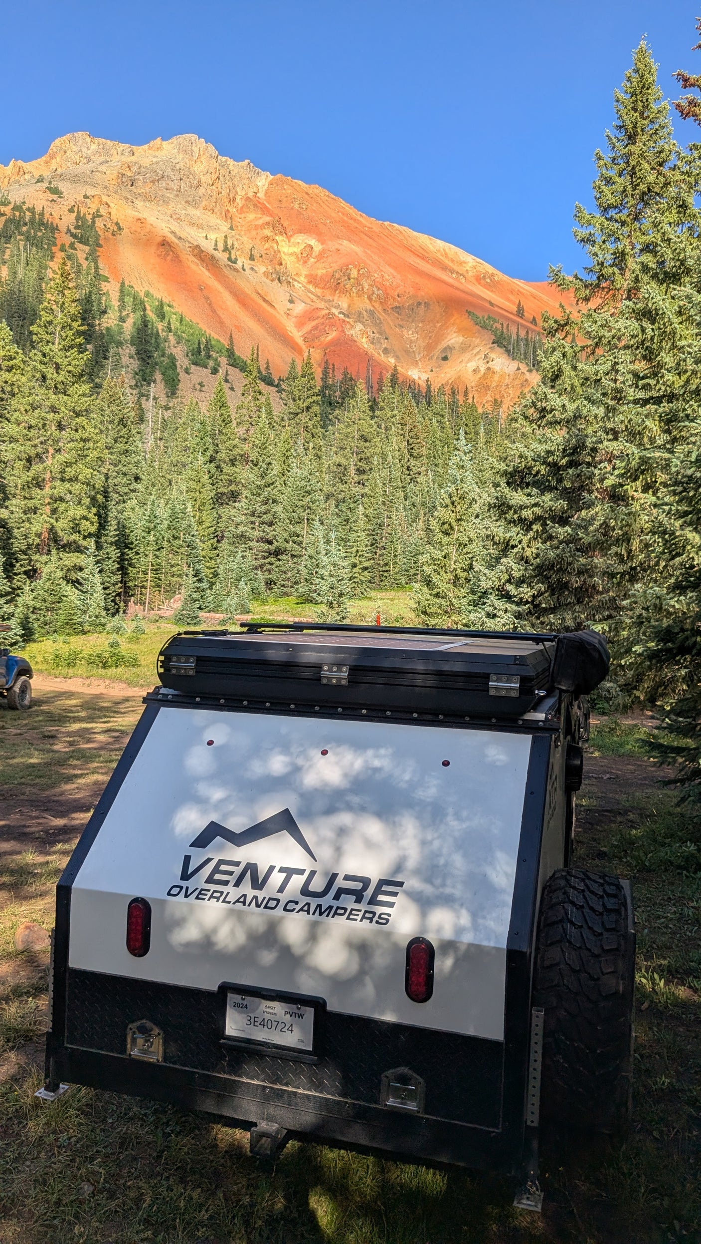 Venture overland RV rental camper with stunning red mountains & forest. Perfect for outdoor camping adventures!