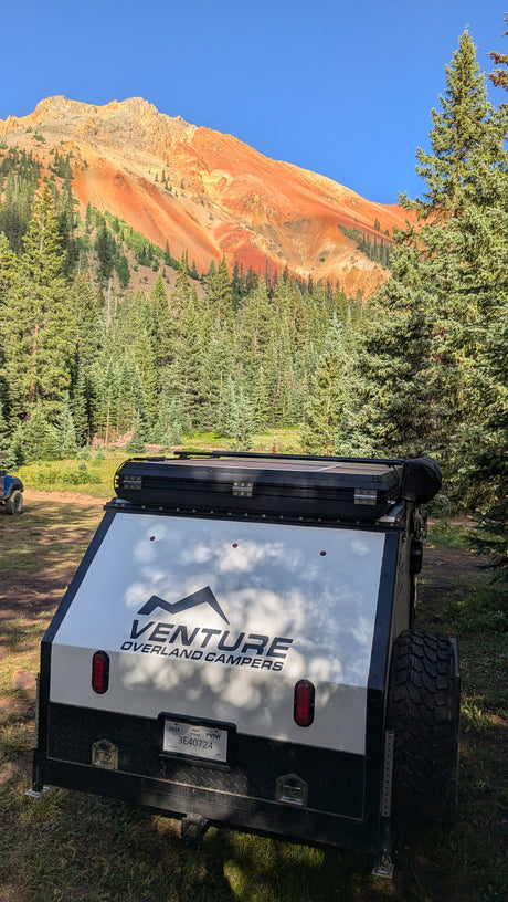 Venture overland RV rental camper with stunning red mountains & forest. Perfect for outdoor camping adventures!