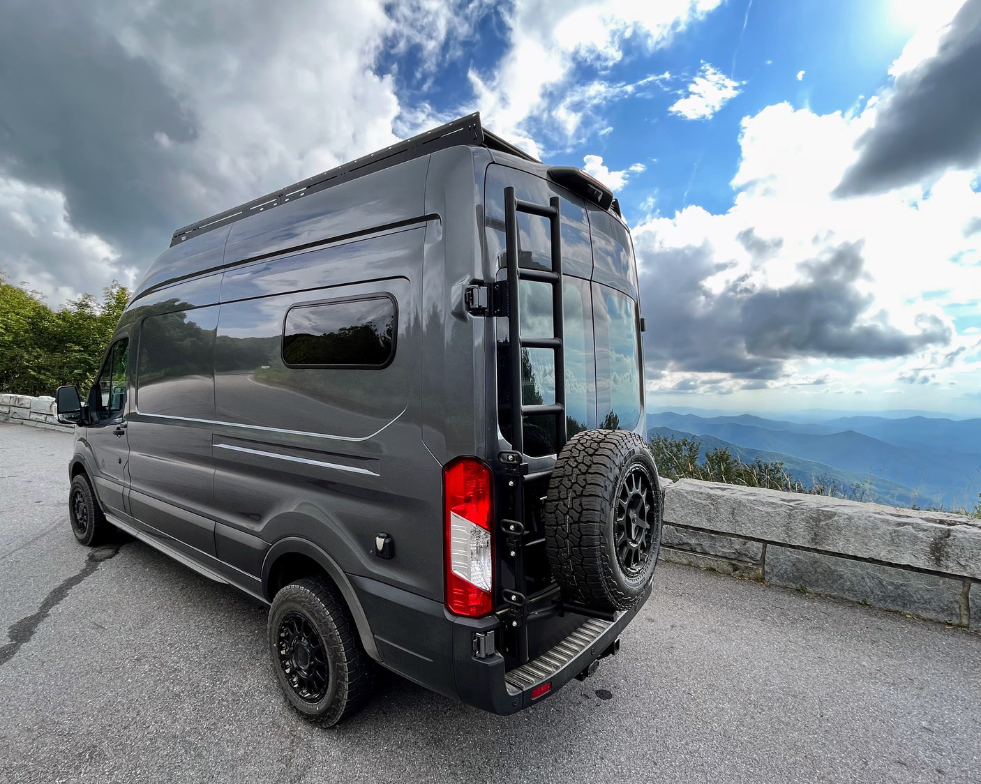 Dark grey camper van parked at a mountain scenic overlook, ideal for an RV rental adventure.