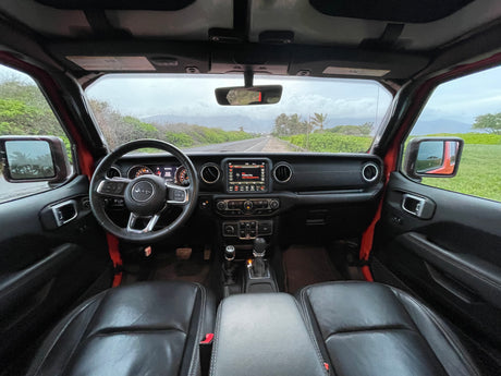 Jeep interior on a scenic road, an adventurous alternative to an RV rental. Dashboard, steering wheel, and tropical views.