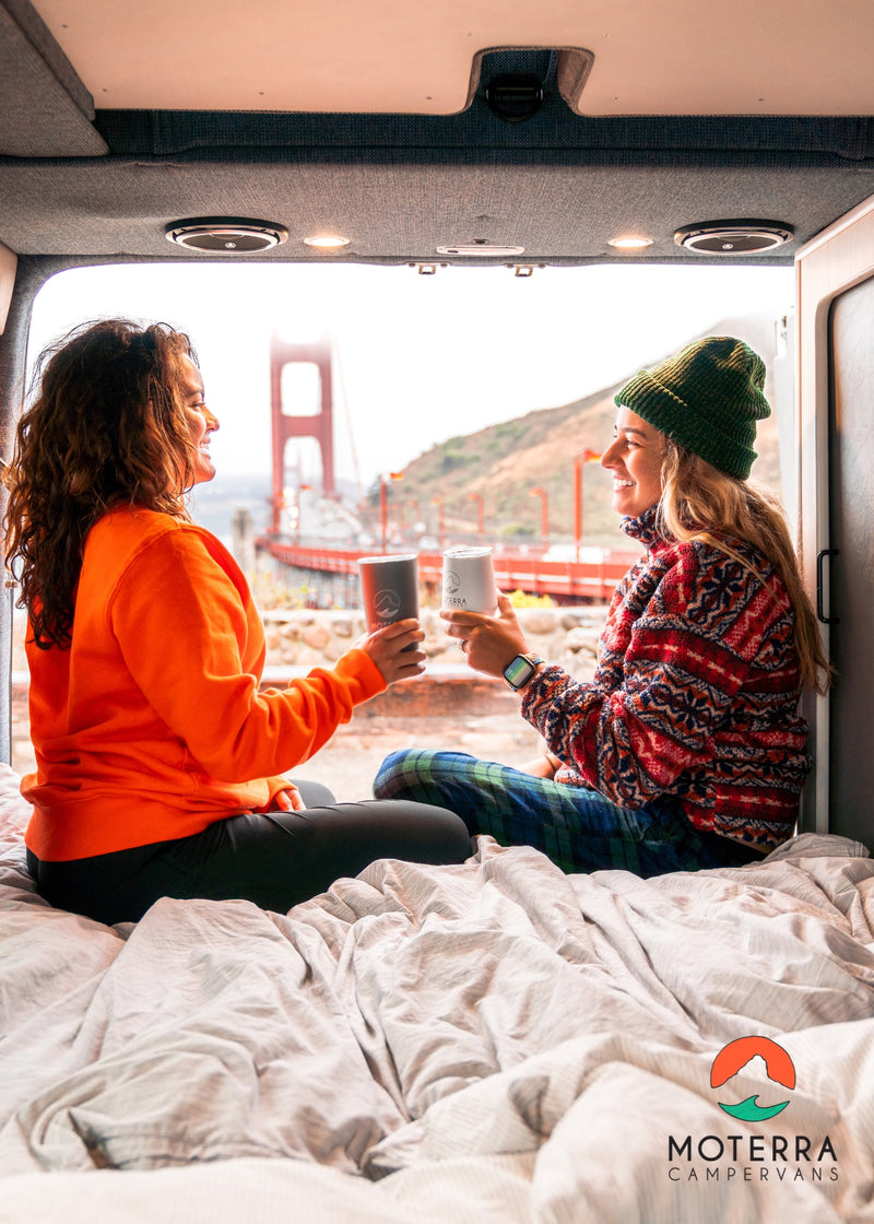  looking out at a foggy Golden Gate Bridge view.|Two friends cozy up on a bed in their RV rental — photo 8