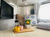 Enjoy a cozy morning in this RV rental! Bed, TV, coffee, and plants make for a comfortable interior.