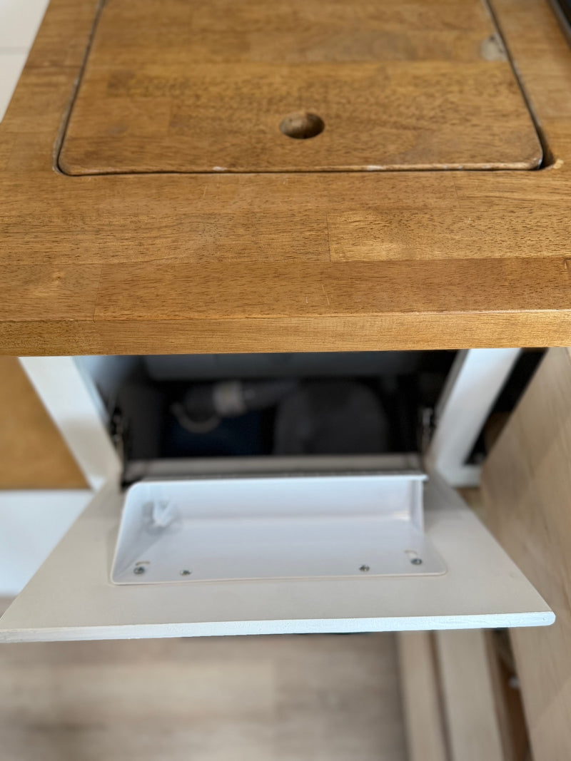 RV rental kitchen: Wooden countertop with a hidden sink cover or cutting board, and an open storage cabinet below. — photo 17