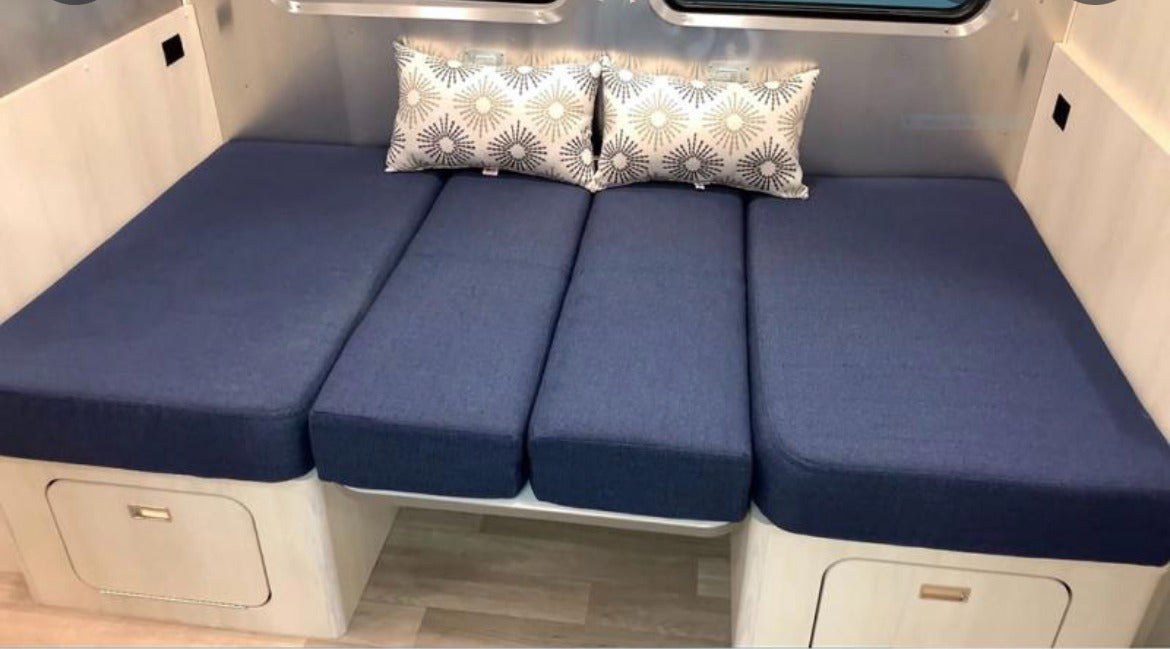 RV rental interior features a blue cushioned bench/bed with decorative pillows and under-seat storage.