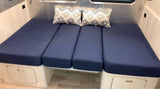 RV rental interior features a blue cushioned bench/bed with decorative pillows and under-seat storage.