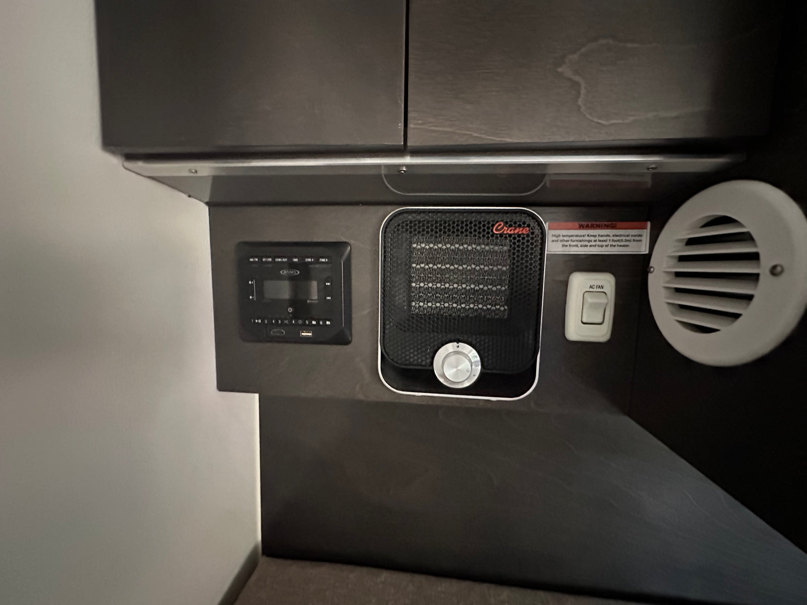 RV rental interior: integrated heater, AC fan switch, and multimedia panel with a safety warning. For comfort & control.