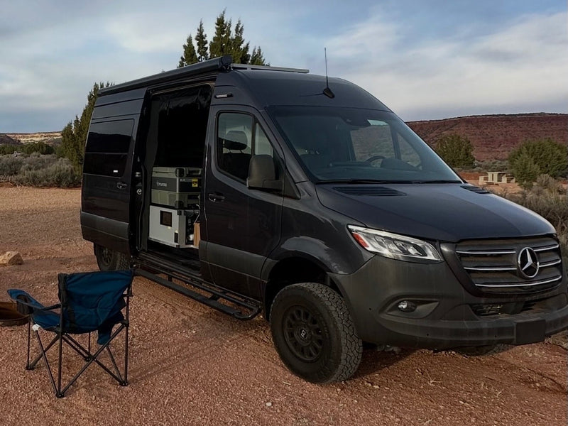 Dark gray Mercedes Sprinter **RV rental** parked in a desert landscape with open side door — photo 1