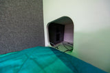 Cozy rv rental sleeping area with a convenient bedside charging station and power outlets built into a modern cubby.