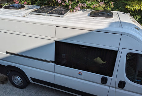 Overhead view of a white camper van: solar panels, roof fans visible. Ideal for an rv rental.