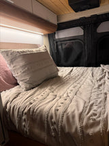 Explore a cozy RV rental interior: soft grey bed, accent lighting, and modern cabinets for comfortable travel.