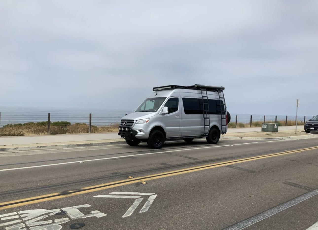  and overhead entertainment system.|Premium RV rental van interior: black leather captain's chairs with red stitching — photo 5