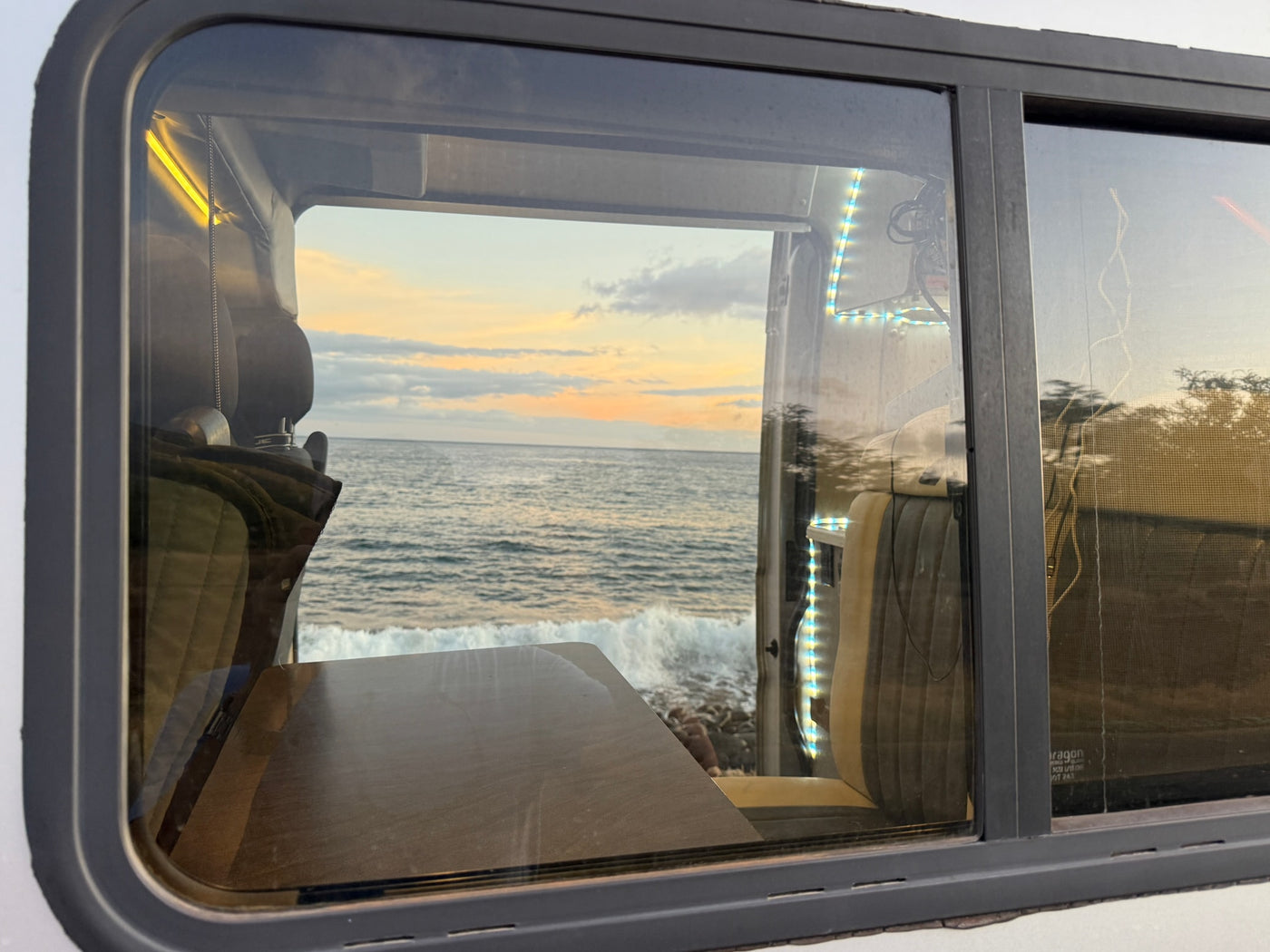 View from an RV rental window: ocean sunset with crashing waves. Your next coastal adventure awaits! — photo 8