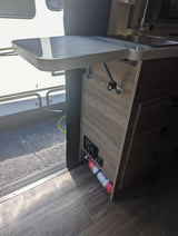 Inside an RV rental: Compact kitchen with a sink, extendable counter, and a fire extinguisher for safety.