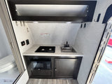 Functional RV rental interior: a compact kitchen with stove, sink, microwave, and adjacent toilet for camper convenience.