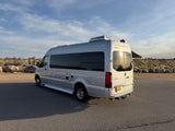 Silver Pleasure Way Sprinter RV rental camper van parked in a sunny, arid landscape with an extended awning.