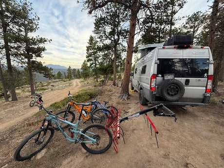 RV rental: Camper van & mountain bikes on a scenic dirt trail, ready for outdoor adventure in the mountains.