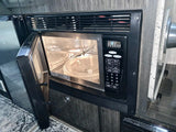 RV rental kitchen: Built-in microwave oven with its door open, revealing the glass turntable for easy meal prep.