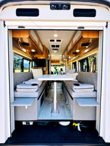 This RV rental features a comfortable interior with twin bench seating, a central table, and overhead cabinets.