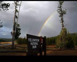 Yellowstone National Park sign under a vibrant rainbow. Your RV rental adventure awaits at this iconic national park.