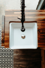 Overhead view of an RV rental kitchen: white sink, dark wood counter, and black pull-down faucet.