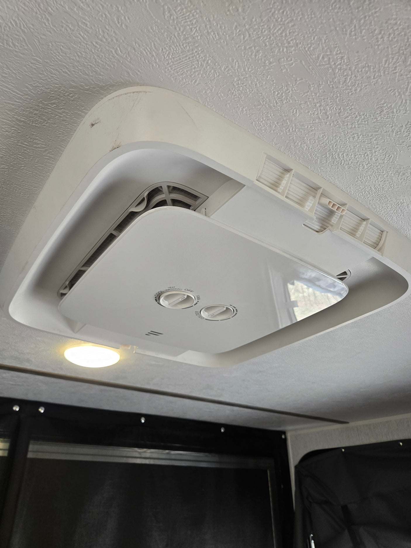 This RV rental's ceiling features a white air conditioner unit with visible control knobs, vents, and an adjacent light.