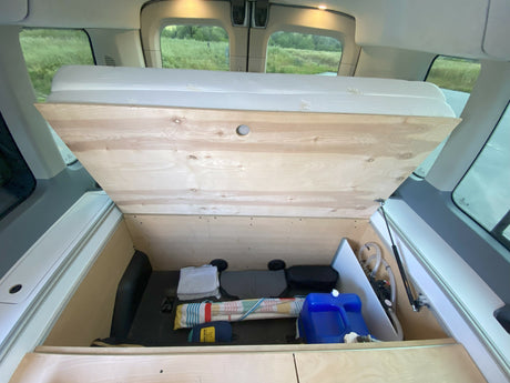 rv rental camper van interior. Lifted bed base reveals ample storage, water system, and gear in the back.