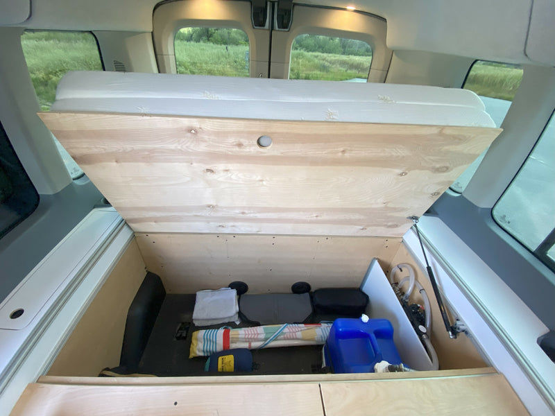 rv rental camper van interior. Lifted bed base reveals ample storage, water system, and gear in the back. — photo 11