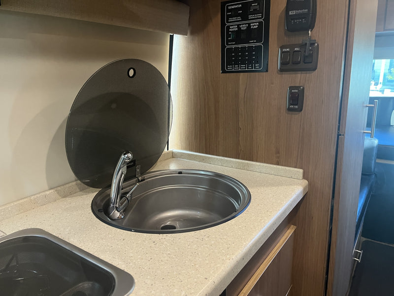 Discover the functional kitchen and control panel in this RV rental, complete with a sink, faucet, and utility readouts. — photo 18