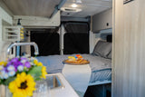 Cozy RV rental interior: bedroom area with chessboard & snacks, plus a compact kitchen. Your road trip starts here!