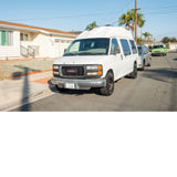 White high-top GMC van, possibly an RV rental, parked on a sunny residential street in California.