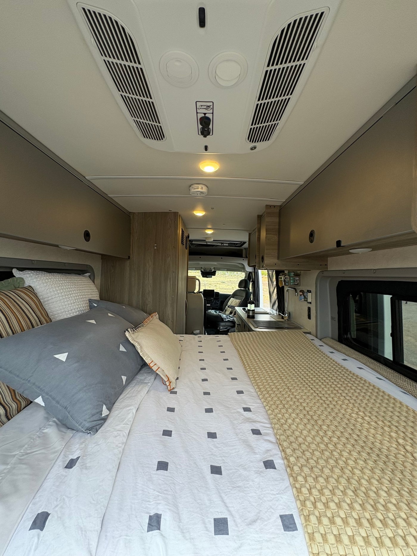 RV rental's inviting interior: features a comfy bed, kitchenette, and driver's cabin with an outdoor view. — photo 7