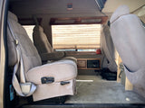 RV rental van interior with tan upholstered seats, pleated window blinds, and a retro cassette player.