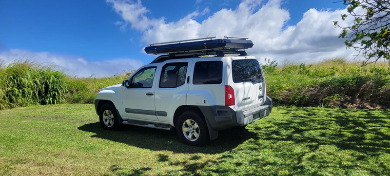White Nissan Xterra SUV, featuring a rooftop tent perfect for an RV rental experience, parked on green grass. — photo 19