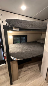 RV rental interior shows bunk beds with mattresses. A warning label on the upper bunk states 300 lbs max capacity.