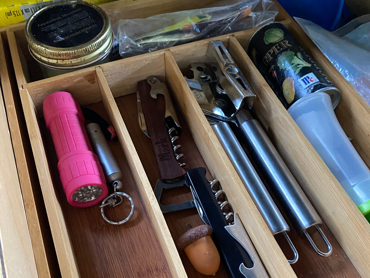 This RV rental's kitchen drawer organizer features a pink flashlight, corkscrews, spices, and cooking utensils, neatly stored. — photo 12