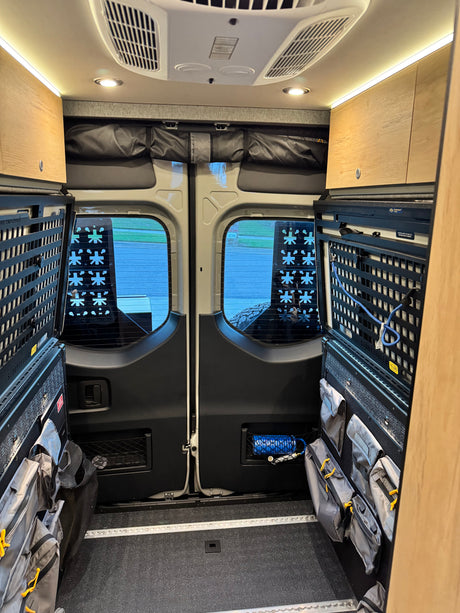 Inside this rv rental: well-equipped camper van interior features modular storage, rear doors, and ceiling lights for adventure.