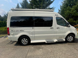 Side view of a white Pleasure-Way Ascent-TS RV rental with tinted windows, parked on a sunny day.