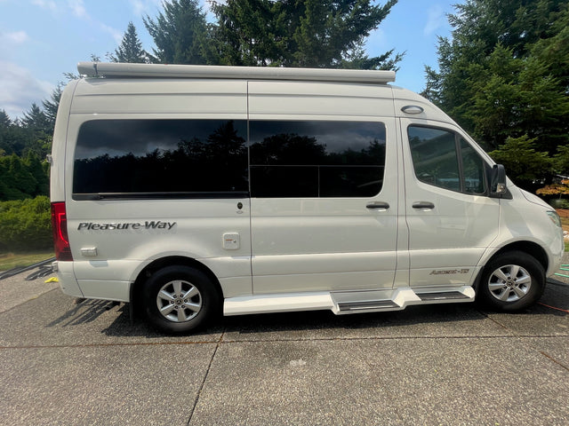 Side view of a white Pleasure-Way Ascent-TS RV rental with tinted windows, parked on a sunny day.