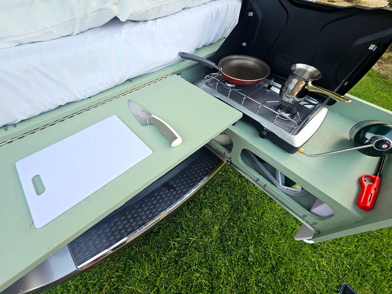 RV rental outdoor kitchen setup. Features pull-out counter with cutting board, stove with pan/pot, and propane lantern. Perfect for camping! — photo 15