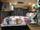 Inviting rv rental interior with "The Adventure Begins" sign, bed, sink, and storage, perfect for travel.