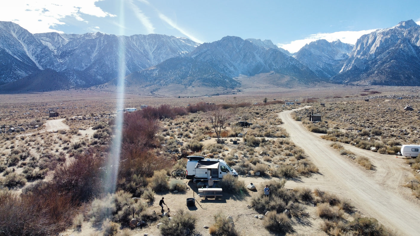RV rental adventure amidst stunning snowy mountains. A camper van parked at a rustic desert campsite.