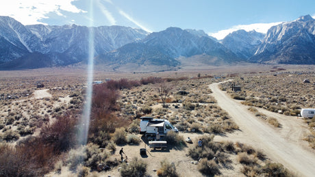 RV rental adventure amidst stunning snowy mountains. A camper van parked at a rustic desert campsite.