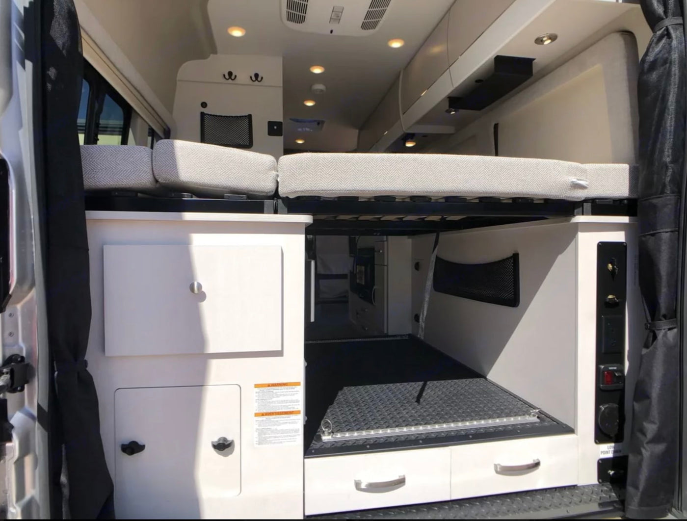  parked on pavers. Features include tinted windows and a roof awning.|RV rental interior: A TV with a colorful label sits beside a built-in cabinet or refrigerator — photo 2