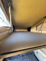 Cozy RV rental pop-up bed interior with canvas walls & support poles, showing a comfortable camping sleep space.