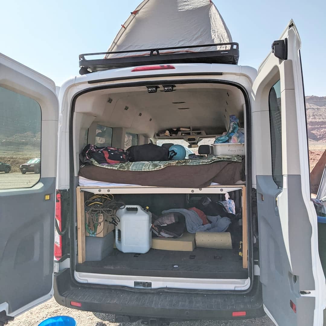  and overhead storage.|White RV rental van with a rooftop tent and ladder — photo 1
